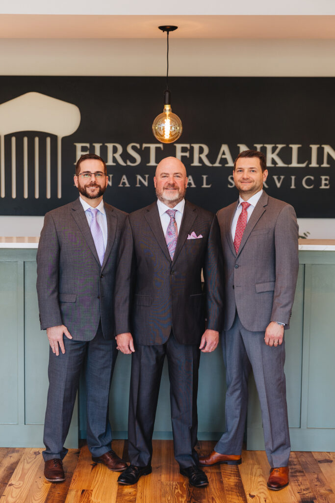Brett Ewing standing with two people inside First Franklin Financial Services.