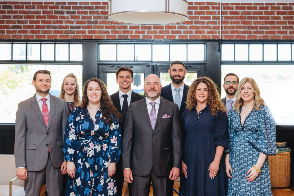 Brett Ewing standing with a group in a professional office environment.