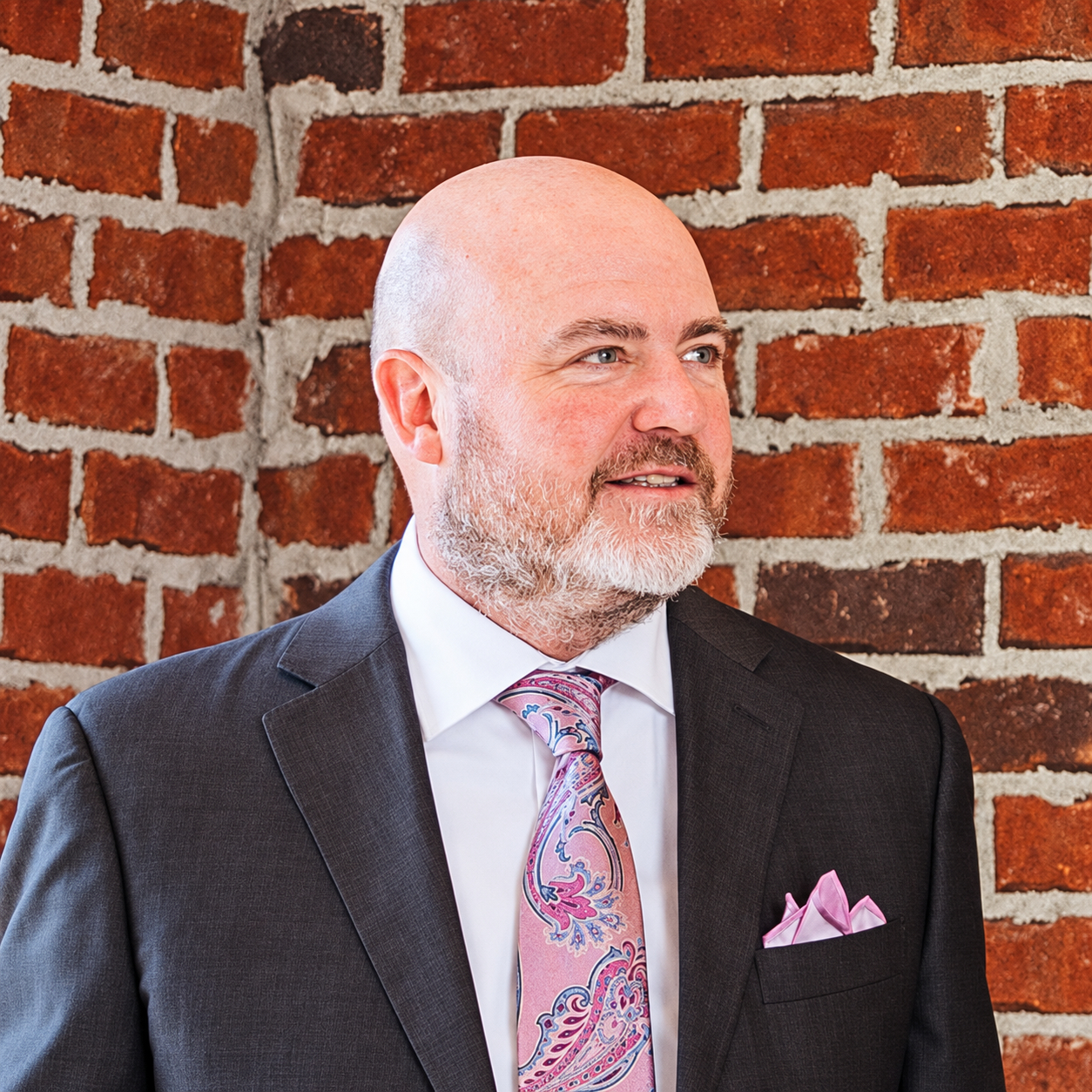 Brett Ewing pictured beside a brick wall in an office setting.